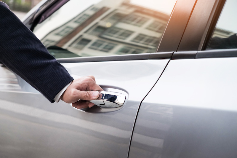 Chauffeur hand on handle of limo